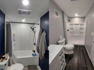 Remodeled bathroom with white tub-shower combo, navy accent walls, dark wood-look plank flooring, and white quartz vanity