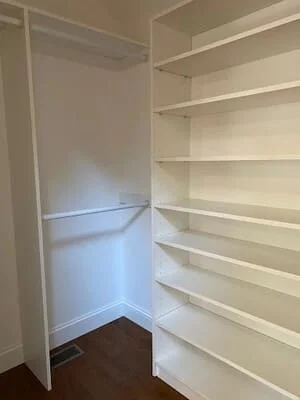 White painted built-in closet shelving and hanging rod with hardwood flooring