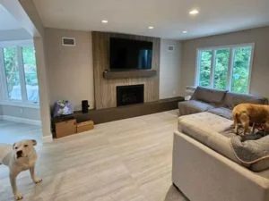 Living room with wood-paneled fireplace wall, wall-mounted TV, built-in wood media cabinet, and wood-look tile flooring