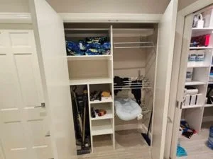 White painted wood closet shelving with open cubbies, chrome hanging rod, and storage bins in a built-in closet